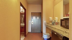 Ein Badezimmer mit Waschbecken, Spiegel und Mikrowelle.