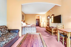 A hotel room with a bed, a sofa, a wooden table, a TV, and a desk with drawers. - Family Friendly Chula Vista Studio/Discount Perks (Wisconsin Dells)