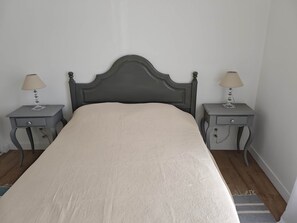 Un lit avec une tête de lit, deux tables de chevet avec des lampes et un tapis sur le sol.