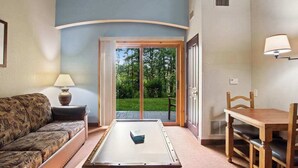Una habitación con sofá, mesa, lámpara y vista a un espacio exterior a través de un ventanal.