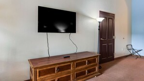 Una habitación con una lámpara, un mueble de madera, una puerta y un televisor de pantalla plana montado en la pared.