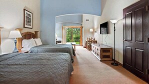 Habitación de hotel con dos camas, un escritorio, un aparador, un televisor y una puerta.