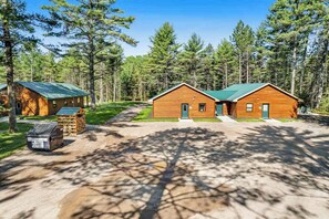 A cabin with a green roof, surrounded by a forest. - Inviting Dog-Friendly Cabin with Hot Tub & AC (Conover)