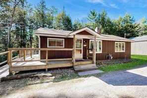Une petite cabane en bois avec une véranda, une petite terrasse et un robinet d’extérieur bien visible.