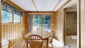 A wooden interior with a dining table and chairs, a large window, and a door leading to an outdoor area. - Dog-Friendly Retreat Near Trails & Lake with Full Kitchen, Central AC, & WiFi (Eagle River)