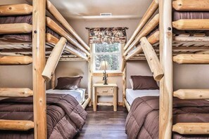 A room with bunk beds, a window with a view, and a small table with a lamp. - Stylish dog-friendly cabin w/hot tub, fireplace, patio, grill, central AC, & W/D (Conover)