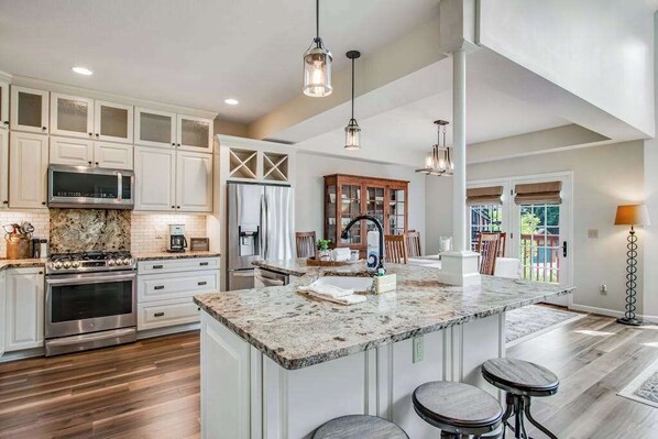 A spacious kitchen with a large island, white cabinetry, and a built-in oven.