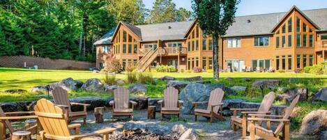 A lodge with a large building, outdoor seating, and a fire pit.