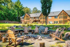 A lodge with a large building, outdoor seating, and a fire pit.