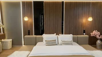 Quarto moderno com uma cama grande, uma mesa de cabeceira, um vaso com flores e uma luminária na parede.