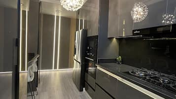 Uma cozinha moderna com eletrodomésticos de aço inoxidável, uma ilha central e iluminação pendente.