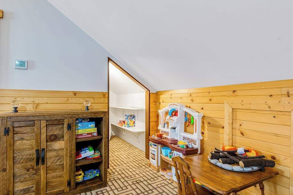 A children's play area with wooden cabinets, toys, and a table with a chair.