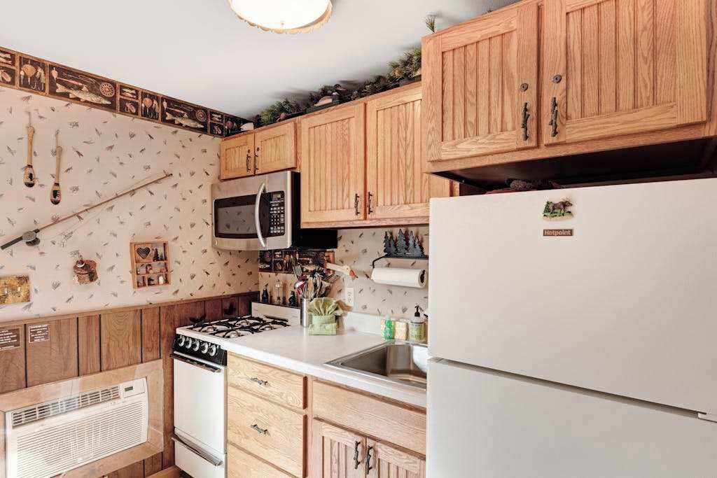 Une cuisine dotée de meubles en bois, d’un four à micro-ondes, d’une cuisinière à gaz, d’un réfrigérateur et d’un four mural.