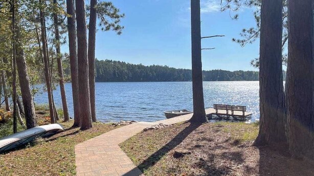 Un sentier qui longe le lac, avec un banc, des arbres et une vue dégagée sur le lac.