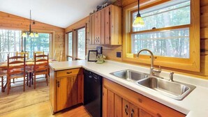 L’intérieur d’une cabane en bois comprend un coin cuisine, une table à manger et des chaises.