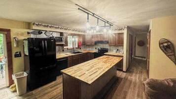 A modern kitchen with a central island, wooden cabinets, and a black refrigerator.