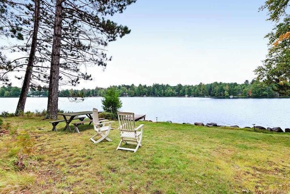 A lakeside setting with a picnic table and Adirondack chairs. - Lakefront home on private peninsula w/ 2 piers & lovely water views - 2 dogs OK (Eagle River)
