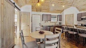 Een keuken met houten kastjes, een eettafel met stoelen en hanglampen.