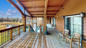 A wooden deck with a railing, a fireplace, and a view of a water body. - Golf-adjacent condo with balcony & arcade (Wisconsin Dells)