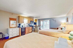 Une chambre d’hôtel avec deux lits, une kitchenette, une petite salle de bain et une vue sur l’extérieur.
