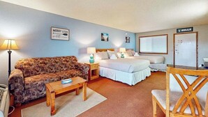 A room with a bed, a sofa, a wooden table, a lamp, and a sign on the wall. - Golf-adjacent condo with balcony & arcade (Wisconsin Dells)