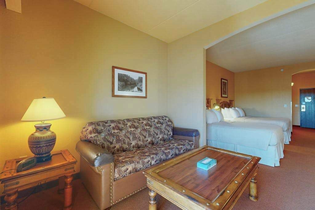 Ein Hotelzimmer mit Sofa, Bett, kleinem Tisch mit Lampe und einem gerahmten Bild an der Wand.