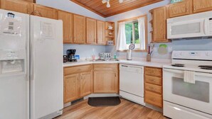 A kitchen with wooden cabinets, a white refrigerator, a microwave, and a stove. - Inviting lakefront stand-alone condo with private beach, boating, & playground (Wisconsin Dells)