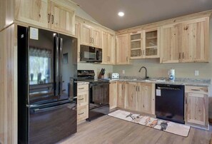 A kitchen with wooden cabinets, a stainless steel refrigerator, a microwave, a dishwasher, and a granite countertop.