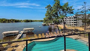 A swimming pool with a view of a lake, a boat dock, and a building with balconies. - Ultimate relaxation awaits at Delton Grand Resort on Lake Delton (Wisconsin Dells)