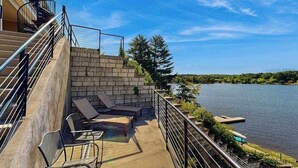 A balcony with outdoor seating, a stone wall, and a view of a lake. - Ultimate relaxation awaits at Delton Grand Resort on Lake Delton (Wisconsin Dells)
