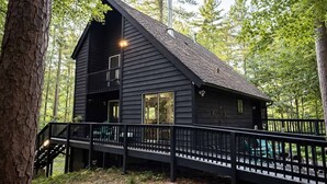 Een chalet met balkon, een trap en uitzicht op het omliggende bos.
