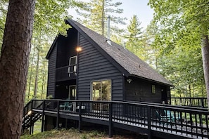 A cabin with a balcony, a staircase, and a view of the surrounding forest. - Amber Sunset Retreat (Lac du Flambeau)