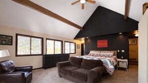 Een slaapkamer met een bed, een dressoir, een stoel en een plafondventilator.