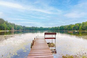 Eine Holzstege, der in einen ruhigen, von Bäumen gesäumten See führt.