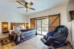 A bedroom with a bed, a ceiling fan, a large window, and a massage chair. - Lakefront escape on Sugar Maple w/ dock, firepit, kayaks, & gas grill- Dogs-OK (Phelps)