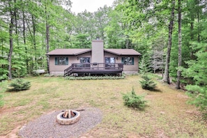 A two-story house with a deck, surrounded by a forest. - Lakefront home with firepit, screened porch, WiFi, central AC, and kayaks (Lac Du Flambeau)