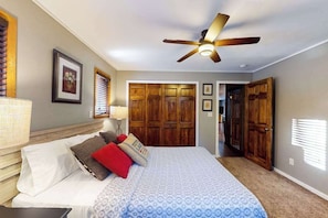 A bedroom with a bed, a ceiling fan, wooden doors, and a hallway. - Private waterfront home with dock, kayaks, firepit, & open layout - dog-friendly (Boulder Junction)