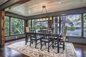 A dining area with a table and chairs, large windows, and a view of trees and water. - Private waterfront home with dock, kayaks, firepit, & open layout - dog-friendly (Boulder Junction)