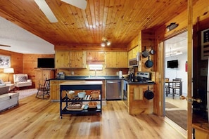 Ein Holzblockhaus-Innenraum mit Küche, Essbereich und Wohnbereich mit Sofa und Fernseher.