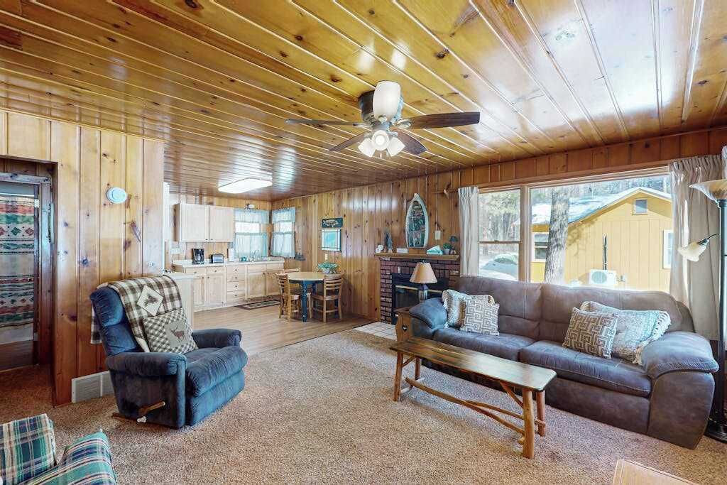A wooden interior with a sofa, armchair, coffee table, and a fireplace.