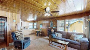 A wooden interior with a sofa, armchair, coffee table, and a fireplace. - Lakeview cabin with dock access, kayaks, row boat, firepit & year-round fun (St. Germain)