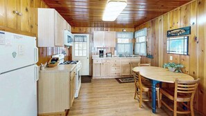 A cabin-style kitchen with wooden walls and a central island. - Lakeview cabin with dock access, kayaks, row boat, firepit & year-round fun (St. Germain)