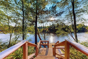 Eine Holzterrasse, die zu einem von Bäumen umgebenen See führt.