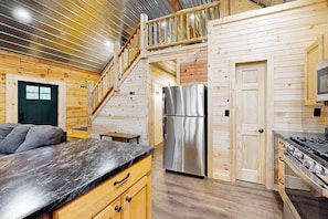 Ein Holzblockhaus-Interieur mit einer Küche, einem Essbereich und einer Treppe.