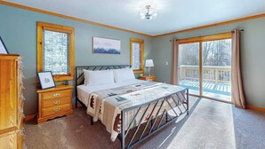 A bedroom with a bed, wooden nightstands, a dresser, a window, and a balcony. - Serene Home w/ large fenced in yard, jetted tub, WIFI, near Lakes & Trails (St. Germain)