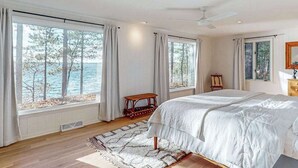 Une chambre avec un grand lit, une vue sur la mer et un ventilateur de plafond.