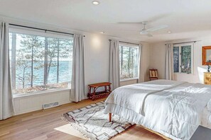 Ein Schlafzimmer mit einem großen Bett, Meerblick und Deckenventilator.