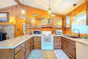A kitchen with wooden cabinets, a stove, a microwave, and a sink.
