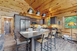 A wooden cabin interior with a kitchen, bar area, and dining space. - Beacon Point  | Lakeside cabin in Presque Isle with a firepit and water access (Presque Isle)