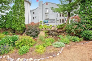 A building labeled 'Lighthouse Cove' with a garden, a pond, and a flag. - Beautiful lakefront home w/free WiFi, full kitchen, shared pool & hot tub (Wisconsin Dells)